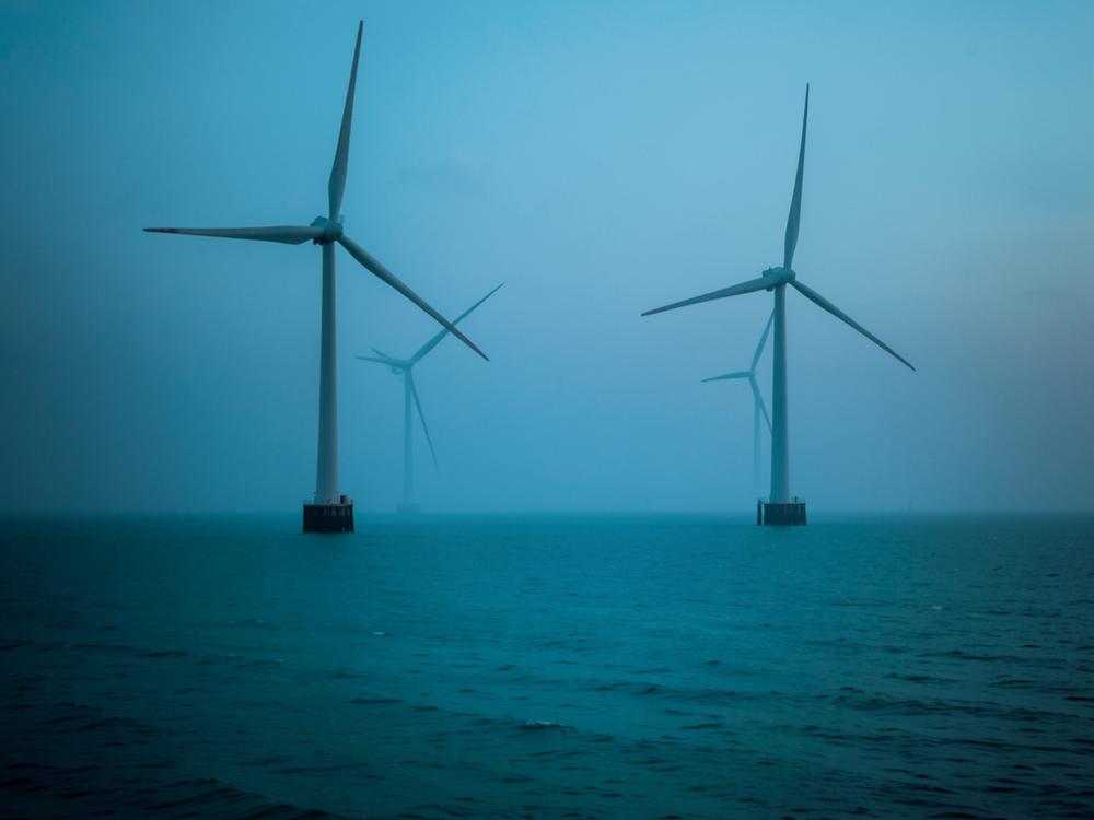 Offshore-Windräder in ruhiger türkisfarbener See zur blauen Stunde